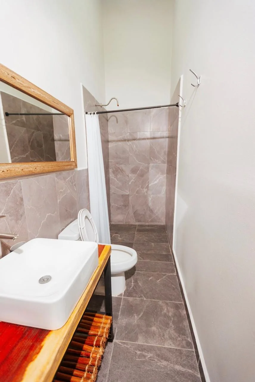 Baño privado con lavabo sobre madera y regadera con cristal